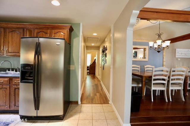 kitchen featuring stainless steel fridge, a sink, light tile patterned flooring, dark countertops, and recessed lighting