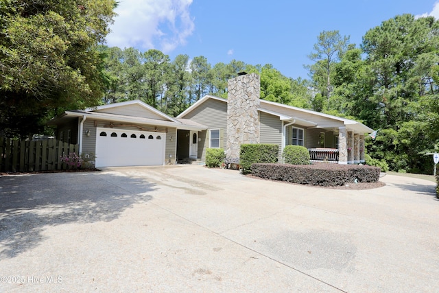 single story home with a garage, concrete driveway, a chimney, fence, and covered porch