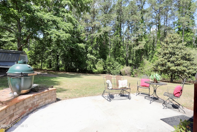 view of patio with view of wooded area, a storage unit, and an outdoor structure