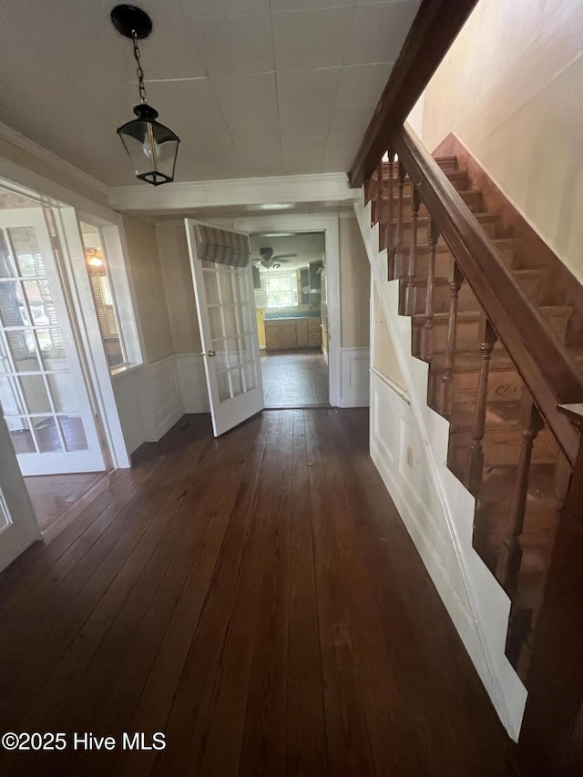 stairway featuring hardwood / wood-style flooring, a wainscoted wall, ceiling fan, crown molding, and french doors