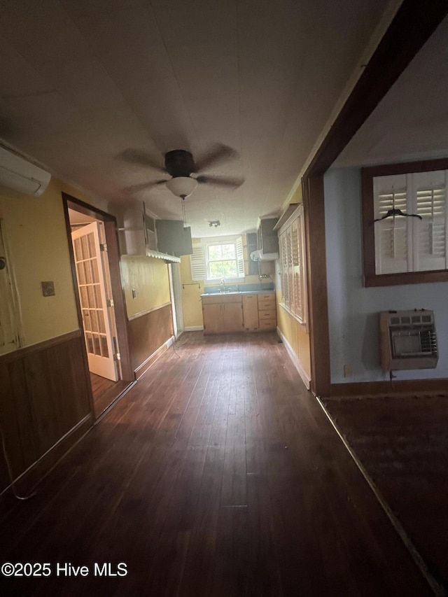 unfurnished room with ceiling fan, a wall mounted air conditioner, dark wood-type flooring, and a sink