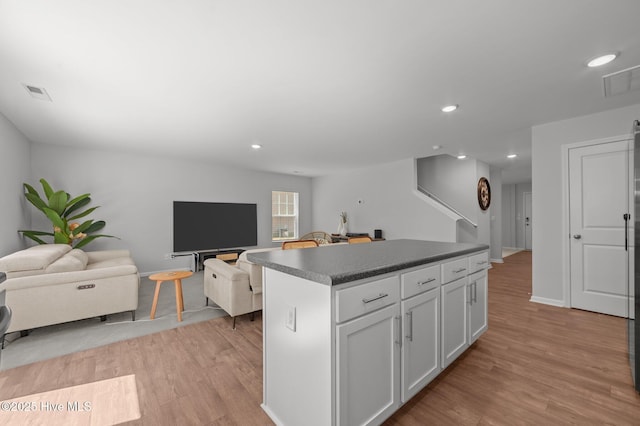 4569 Sandstone Dr, Greenville, NC 27858 - kitchen featuring a center island, dark countertops, light wood-style floors, white cabinetry, and recessed lighting