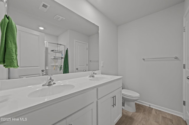 4569 Sandstone Dr, Greenville, NC 27858 - full bathroom featuring a shower stall, wood finished floors, toilet, double vanity, and baseboards