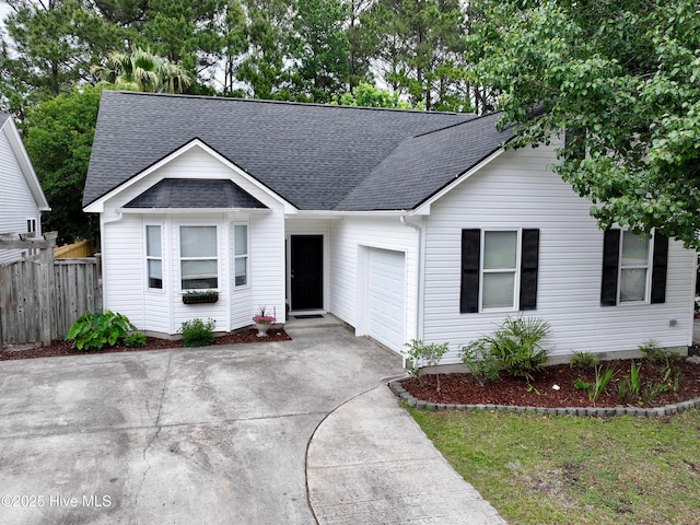 view of front of property with a shingled roof, a garage, fence, and concrete driveway