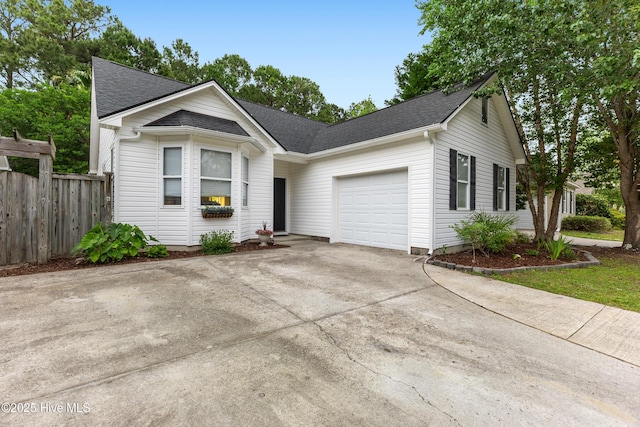 ranch-style home featuring an attached garage, fence, concrete driveway, and a shingled roof