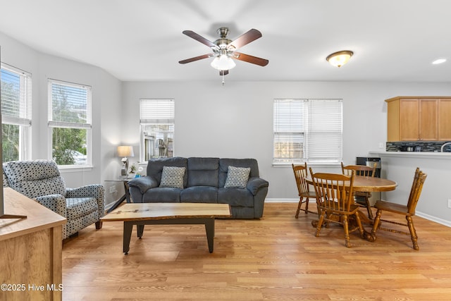 living room featuring light wood-type flooring, a ceiling fan, and baseboards