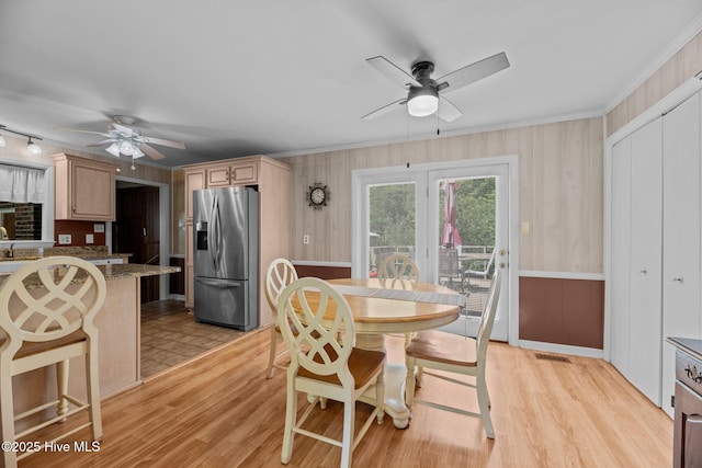 dining room with a ceiling fan, ornamental molding, and light wood-type flooring