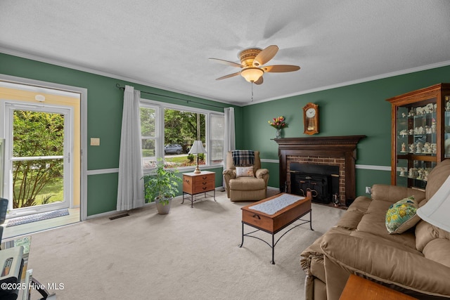 carpeted living area featuring a ceiling fan, a textured ceiling, a fireplace, crown molding, and baseboards