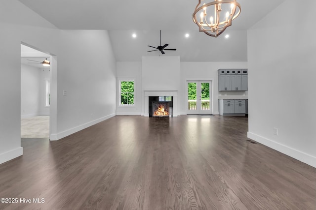 140 E Ag Dr, New Bern, NC 28562 - unfurnished living room with a ceiling fan, a warm lit fireplace, high vaulted ceiling, baseboards, and a chandelier