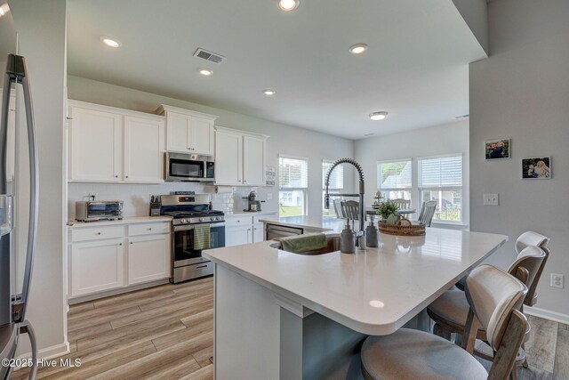6909 English Holly Ct SW, Ocean Isle Beach, NC 28469 - kitchen featuring appliances with stainless steel finishes, a sink, decorative backsplash, a kitchen breakfast bar, and light countertops