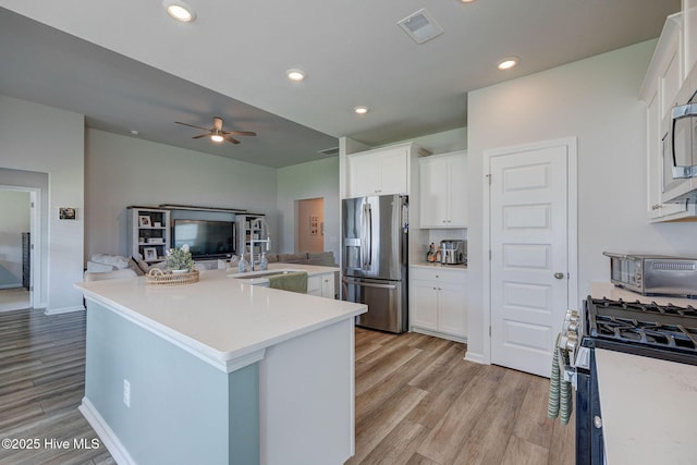 6909 English Holly Ct SW, Ocean Isle Beach, NC 28469 - kitchen with appliances with stainless steel finishes, light wood-style floors, white cabinetry, a ceiling fan, and light countertops