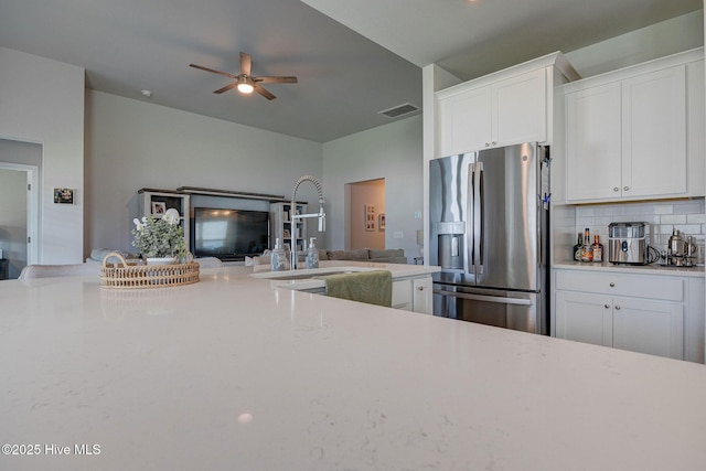 6909 English Holly Ct SW, Ocean Isle Beach, NC 28469 - kitchen with stainless steel fridge, a sink, white cabinets, a ceiling fan, and backsplash