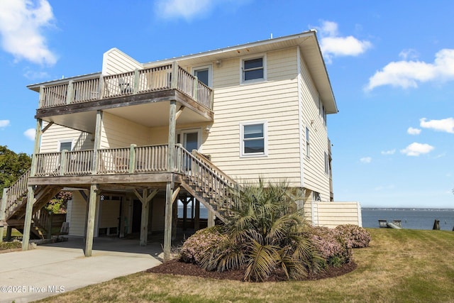 back of house with stairs, a balcony, concrete driveway, and a carport
