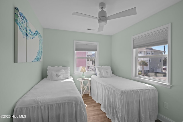 bedroom featuring multiple windows, wood finished floors, ceiling fan, and baseboards