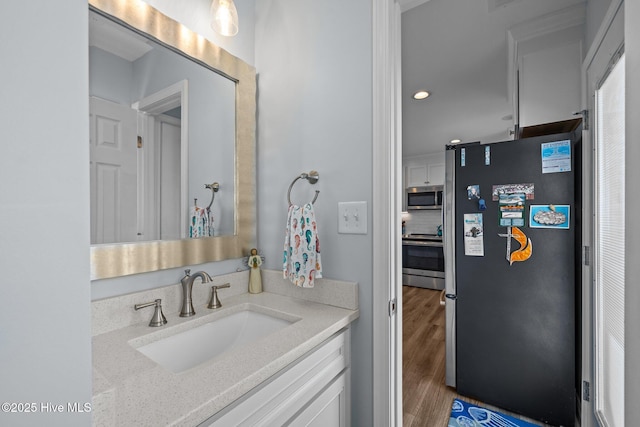 bathroom with wood finished floors, vanity, and recessed lighting
