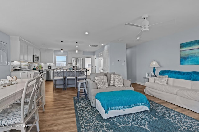 living area with a ceiling fan, wood finished floors, recessed lighting, and baseboards