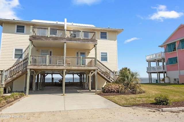 rear view of house with a carport, stairs, a balcony, a water view, and driveway