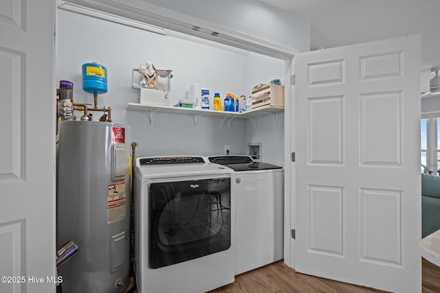 washroom with electric water heater, washing machine and dryer, and wood finished floors