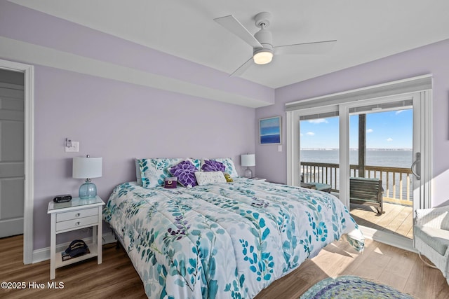 bedroom with access to outside, a water view, wood finished floors, and a ceiling fan