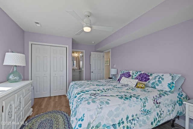 bedroom featuring wood finished floors, a closet, ceiling fan, and connected bathroom