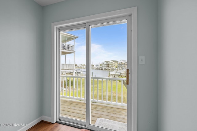 doorway to outside featuring a water view, baseboards, and wood finished floors