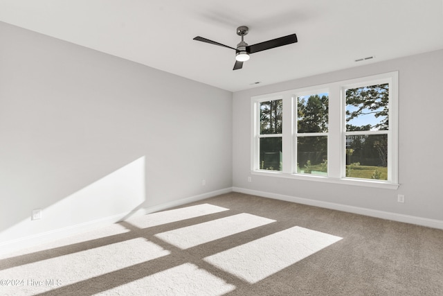 carpeted spare room featuring baseboards and a ceiling fan
