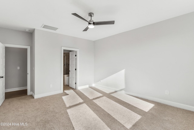 unfurnished bedroom with light colored carpet, baseboards, ceiling fan, and ensuite bath