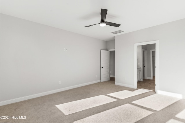 unfurnished bedroom featuring light carpet, baseboards, ensuite bathroom, and ceiling fan