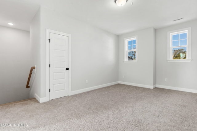 empty room with plenty of natural light, light carpet, and baseboards