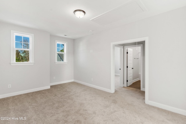 unfurnished bedroom with attic access, carpet flooring, and baseboards