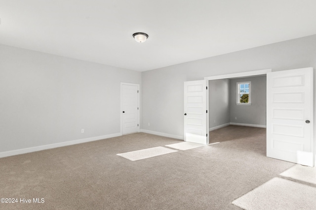 unfurnished bedroom featuring light carpet and baseboards