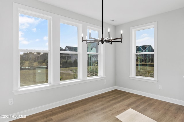 unfurnished dining area featuring a chandelier, wood finished floors, and baseboards