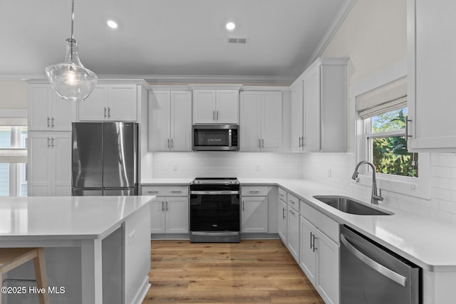 921 Whitecaps Ln, Carolina Beach, NC 28428 - kitchen with appliances with stainless steel finishes, a sink, light countertops, backsplash, and decorative light fixtures