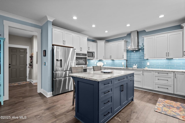 3528 Cordgrass Ln, Wilmington, NC 28409 - kitchen with appliances with stainless steel finishes, wall chimney range hood, white cabinetry, ornamental molding, and a kitchen island