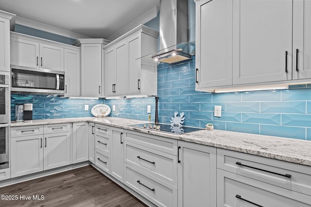 3528 Cordgrass Ln, Wilmington, NC 28409 - kitchen with wall chimney exhaust hood, stainless steel microwave, black electric stovetop, white cabinetry, and tasteful backsplash