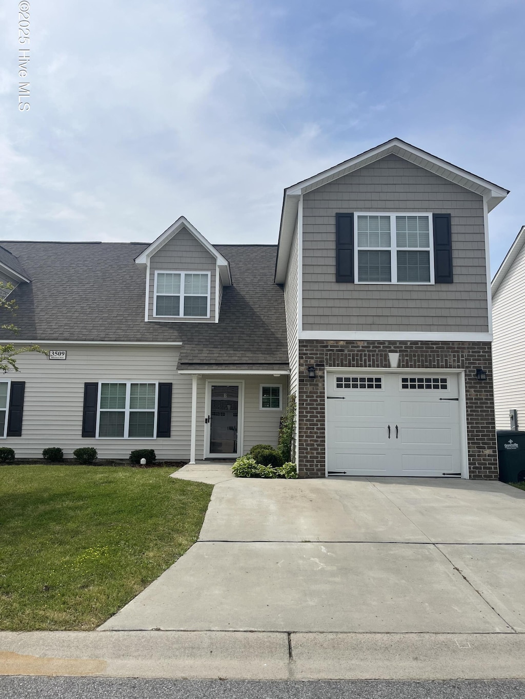 view of front of house featuring driveway, a front yard, an attached garage, and a shingled roof