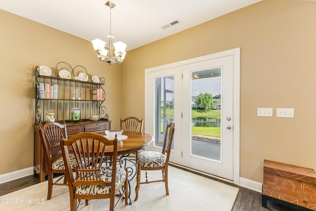 dining space with a chandelier, baseboards, wood finished floors, and a water view
