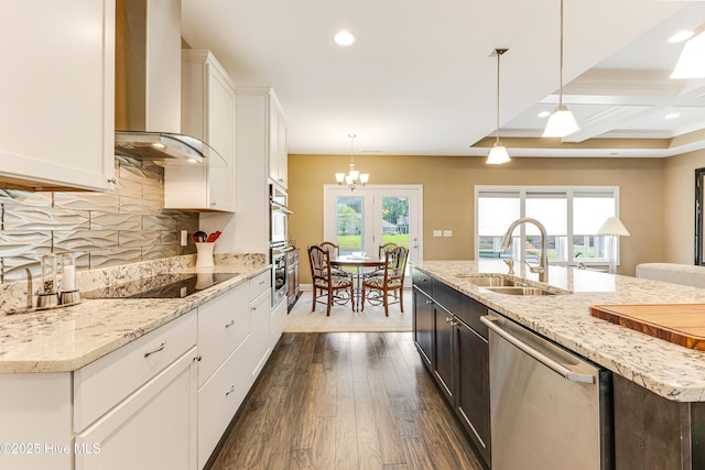 kitchen featuring stainless steel dishwasher, wall chimney exhaust hood, black electric cooktop, a sink, and white cabinetry