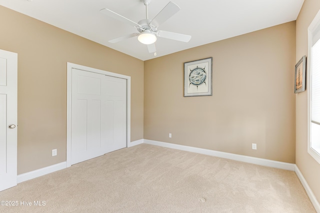 unfurnished bedroom with light colored carpet, baseboards, a closet, and multiple windows