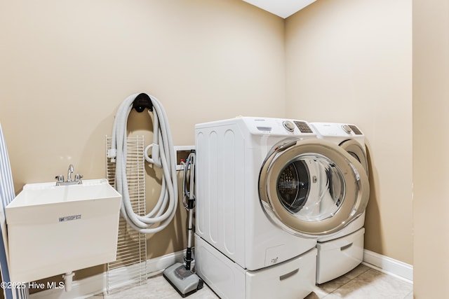 clothes washing area featuring washing machine and dryer, baseboards, and light tile patterned floors