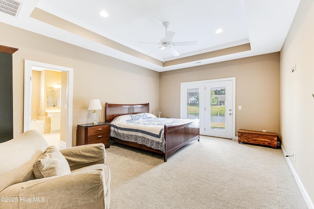 bedroom featuring access to outside, a tray ceiling, light carpet, recessed lighting, and ensuite bathroom