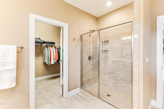bathroom with a stall shower, a walk in closet, and baseboards