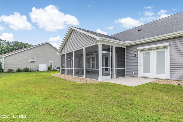 back of property featuring a sunroom, a yard, roof with shingles, and a patio area