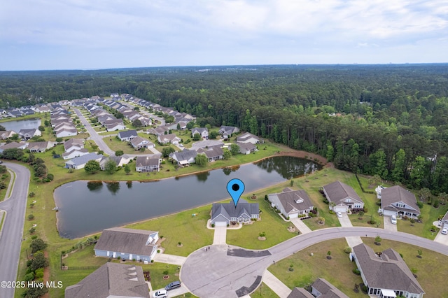 view of property location featuring a forest, a large body of water, and nearby suburban area