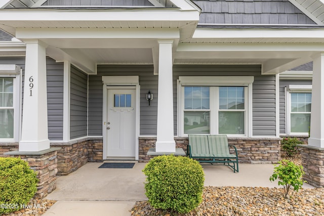 doorway to property with covered porch and stone siding