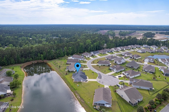 view of property location featuring a nearby body of water, a forest, and nearby suburban area