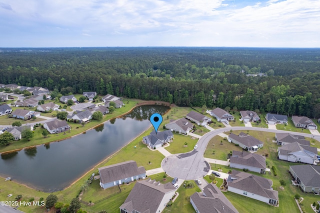 aerial view of property and surrounding area with a heavily wooded area, a nearby body of water, and nearby suburban area