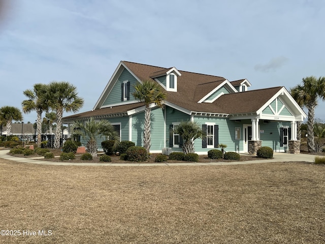 view of front facade with a shingled roof and a front yard