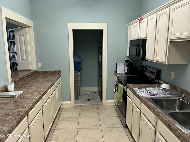 kitchen with black microwave, electric stove, dark countertops, a sink, and light tile patterned floors