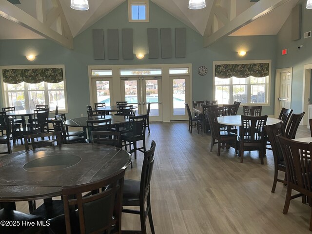 dining area featuring high vaulted ceiling, french doors, plenty of natural light, and wood finished floors
